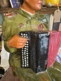Close-up of the accordion showing red bellows, black casing, and white buttons painted in relief.