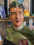 Detail of the soldier’s face with painted features, wearing a green military cap with red star.