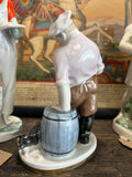 Side-rear angle of the porcelain cook figurine, highlighting the chef’s slumped posture and the curious cat beside the barrel, with fine brushwork on the clothing and glaze.