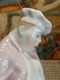 Detail of the cook’s face from the Lomonosov figurine “The Cook and the Cat,” showing a downcast expression and hand-painted facial features under a tilted chef’s hat.