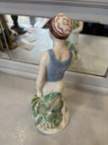 Angled rear-top view showing the decorative red and white star motif on the boy’s traditional cap and the glossy green details of the sculpted foliage.