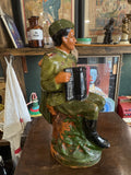 Left-side profile of the statue, showing the accordion from the side and shoulder epaulettes on the uniform.
