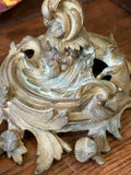 Detailed close-up of the decorative Rococo base of an antique brass candelabra.