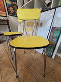 Vintage yellow Formica chair with arm, front view, showing chrome hairpin legs and crisscross back support.