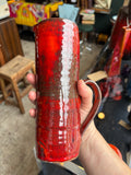 	Hand holding mid-century pottery jug to show scale and glaze detail