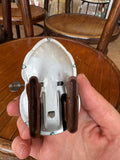 Underside of vintage tin wind-up dog toy showing mechanism, wheels, and wind-up key held in hand.