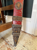 Close-up of the scabbard’s lower portion, featuring a portrait medallion, laurel banding, and a chape decorated with a temple and bird motif.