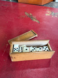 Wooden box open showing miniature bone domino tiles inside