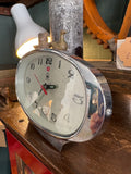 Three-quarter side view of 1970s Treasure oval alarm clock showing polished chrome oval case profile with alarm set screw on right side
