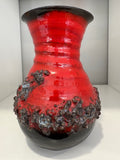 Vintage West German fat lava vase in red and black volcanic glaze, front view on white background