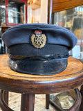 RAF airman service dress peaked cap in blue-grey wool with embroidered Queen's crown badge, displayed on a bentwood chair 