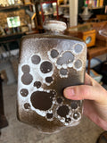 Hand holding Strehla vase showing scale and crater texture
