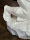 Porcelain figure's foot and base showing soft sculptural folds and glaze texture