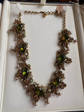 Full view of signed Florenza vintage necklace laid flat in cream box, showing peridot green marquise rhinestones, amber rhinestone clusters, and faux seed pearl drops on antiqued gold tone metal.