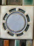 Close-up of circular ceramic motif in Anne Plant wall hanging.