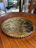 Arts and Crafts brass dish with repoussé Celtic knot design and crimped pie crust rim, on a wooden chair 