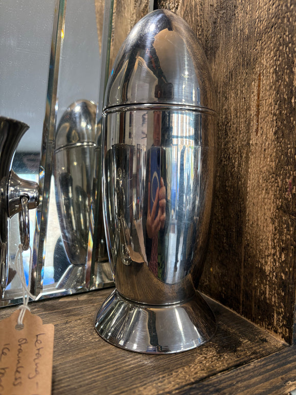 Vintage Art Deco rocket-shaped stainless steel cocktail shaker on wooden shelf. 