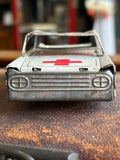 Front view of vintage 1960s Japanese tinplate ambulance showing pressed steel grille and red cross bonnet panel
