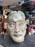 Plaster maquette head shown among shop ceramics