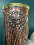 Close-up of embossed foliate and grape design below brass rim