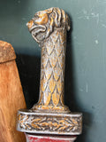 Close-up of the sword’s lion-head pommel and grip, cast in metal with gold and silver painted detailing.