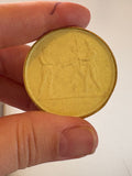 Wax medallion held between fingers showing scale, approximately 4cm across