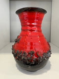 Mid century red fat lava vase photographed straight-on against plain backdrop