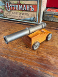 Miniature scratch-built brass cannon on wooden carriage with brass wheels, three-quarter view