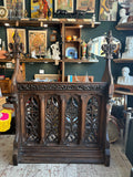 Front view of an antique Gothic Revival carved oak lectern with pierced tracery panels and tall carved finials, displayed in an antique shop