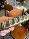 Close-up of the crimped pie crust rim of a brass dish, with darkening inside the crimps