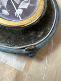 Close-up of clasp and velvet lining on antique shield-shaped photograph case. 