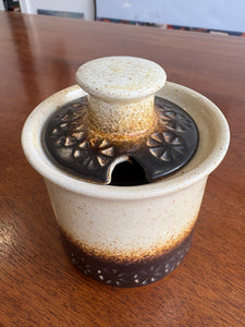 1970s Iden Pottery mustard pot with cream to brown glaze, embossed daisy motif, and matching lid. 9cm high.