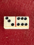 Close-up of a single bone domino tile showing black pips and red dividing line