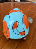 Vintage tin wind-up dog toy viewed from behind, showing orange and blue tin litho pattern and wind-up key.