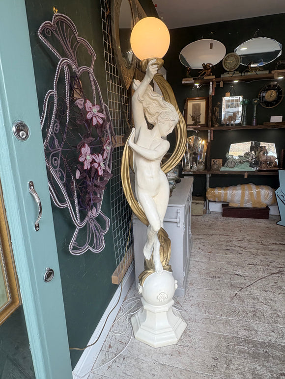 Large white and gold resin floor lamp with dancing female figure holding a glass globe shade. 