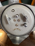 Close-up of rear mechanism plate of Treasure oval alarm clock showing control knobs, screws, alarm and hand-wind levers 