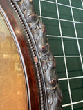 Close-up detail of the upper right section of the oval Victorian portrait frame showing the carved acorn and leaf relief moulding with visible age-related cracking and surface wear, and the inner beaded moulding edge.