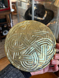 Reverse of an Arts and Crafts brass dish showing the hammered-out back of the Celtic knot design
