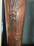 Detail of repoussé poppy flowers and stem lines on copper vase body