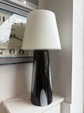 Close-up side view of Habitat Joséphine black glass lamp base showing high-gloss black glass with white oval panel detail and white shade above