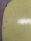 Close-up of yellow woven Formica surface showing texture, minor wear, and small edge chip.