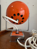 Rear view of orange 1970s space age eyeball lamp showing ventilation holes and chrome bracket mount