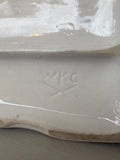 Close-up of the impressed WKC mark on the underside of the figurine, located within a cross or branch motif.