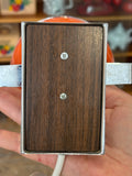 Underside view of base of vintage orange space age eyeball lamp showing walnut-effect wooden panel and chrome surround