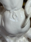 Detail of rear view of porcelain figure, showing tied apron and smooth glaze