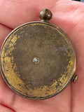 Reverse of brass button compass case, held in hand