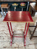Chinoiserie red and gold painted side table, front view showing full height, four turned faux bamboo legs with horizontal gold banding, H-stretcher with central turned spindle, and curved bracket feet.