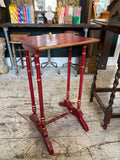 Early 20th century Chinoiserie style painted wooden side table, three-quarter front view, showing red painted rectangular top with gilt dragonfly and botanical decoration, four faux bamboo turned legs with gold bands, and H-stretcher base.