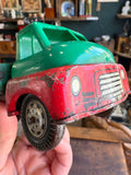 Hand holding vintage Wells-Brimtoy tinplate toy truck showing front cab detail and paint wear