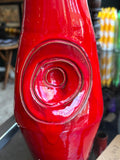 Close-up of raised spiral medallion on red drip glaze vase